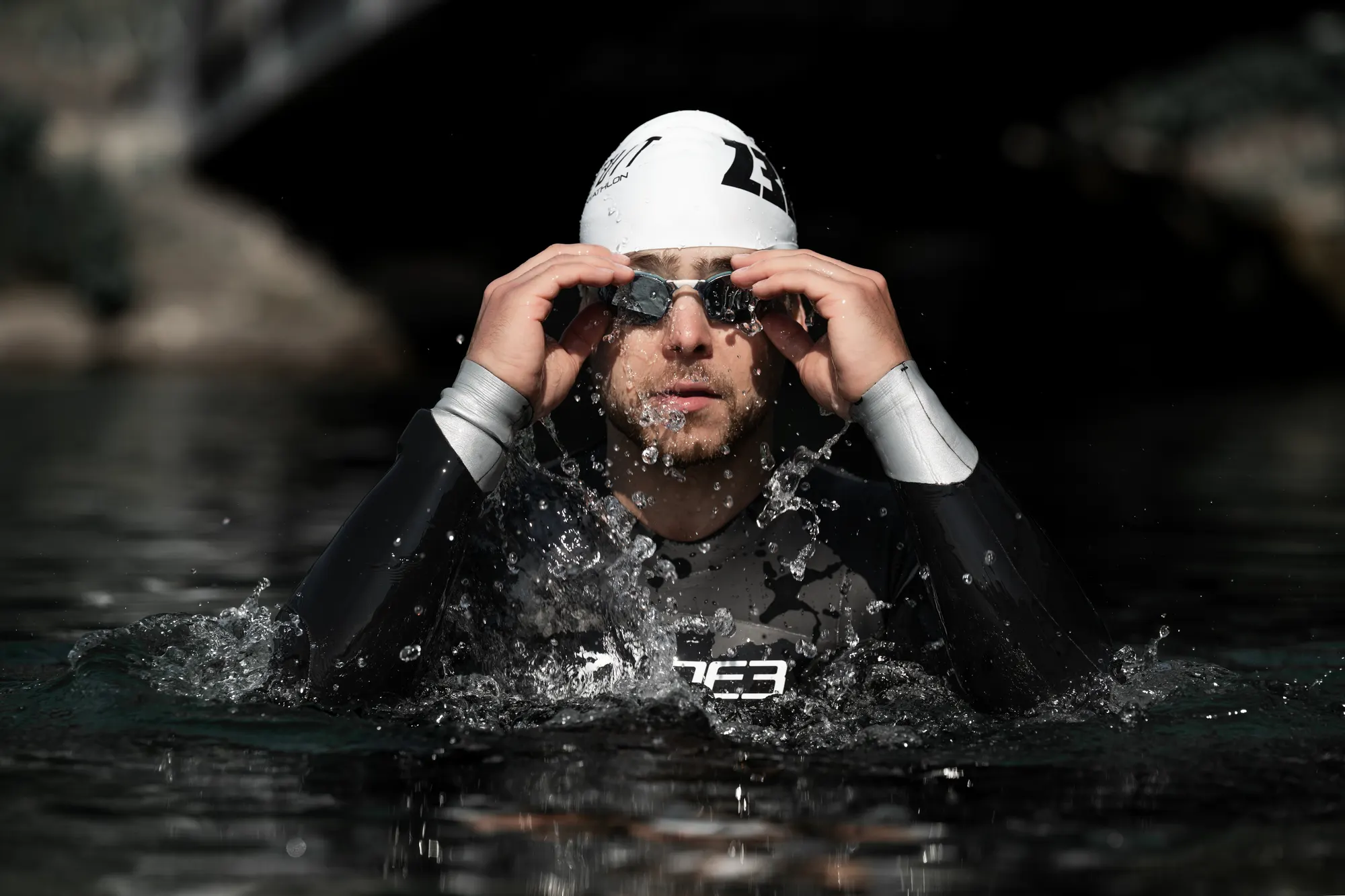 Samir Serhani im Neoprenanzug zieht im Wasser seine Schwimmbrille zurecht